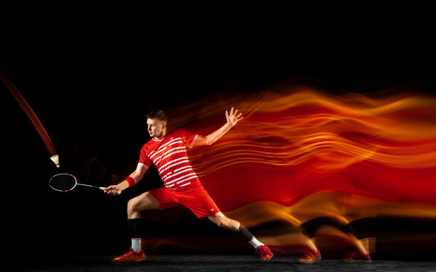 年轻男子打羽毛球孤立在黑色演播室背景图片下载