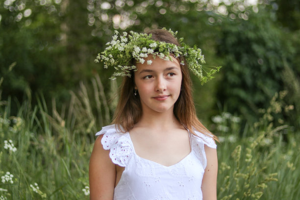 美丽浪漫的少女与绿色和白色的鲜花花环在户外的头。接近大自然。自然美景图片下载