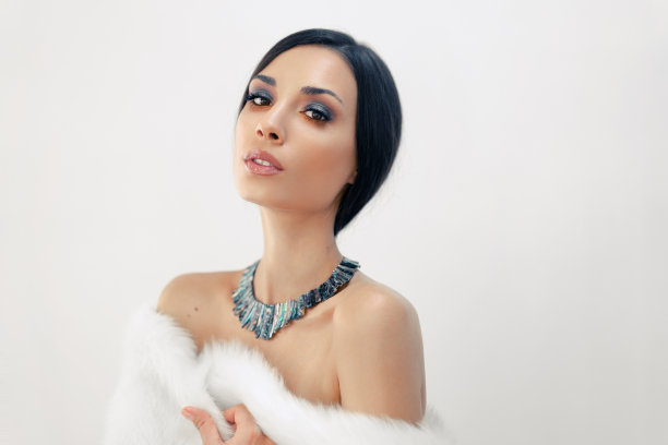 一个美丽的年轻白人女孩的肖像赤裸的肩膀和美丽的晚上化妆穿着人工白色毛皮图片下载