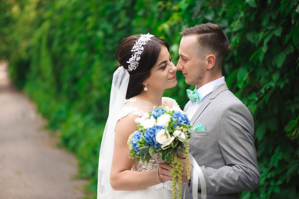 新娘和新郎在公园接吻。一对新婚夫妇新娘和新郎在一个婚礼在自然绿色的森林正在亲吻照片肖像。婚礼的夫妇图片下载