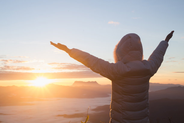 女人把双手举向天空，感谢上帝，清晨日出的背景，基督教观念的背景。图片下载