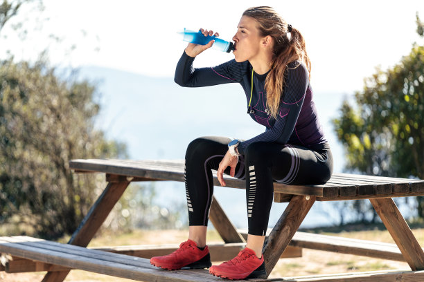 跑步者喝着水，坐在长凳上，在山顶上放松片刻。图片下载
