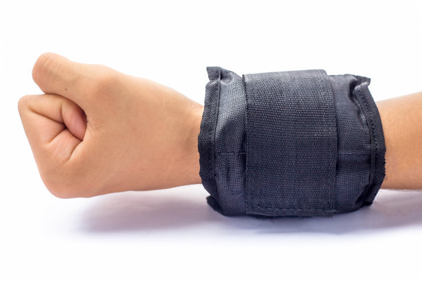 近距离的人的手戴着黑色的手腕重量在他的手和做运动孤立在白色。图片下载