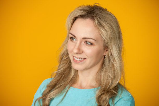 一个在黄色背景上的30岁金发女人的工作室肖像图片下载