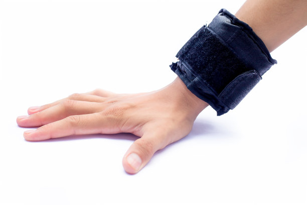 近距离的人的手戴着黑色的手腕重量在他的手和做运动孤立在白色。图片下载