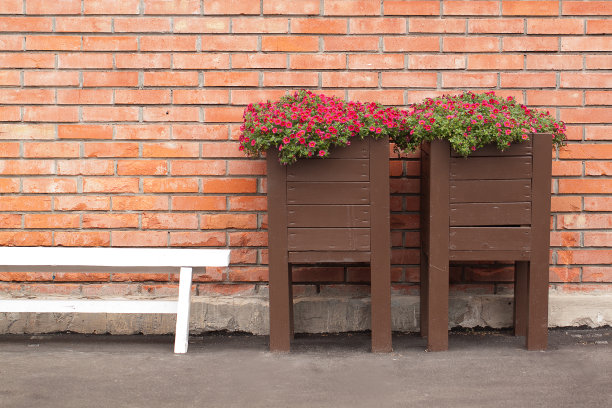 一个放松的地方，有长凳和鲜花靠近砖墙图片下载