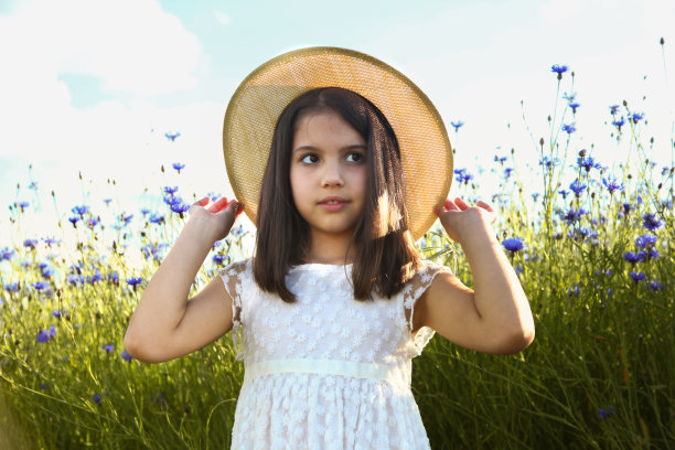 快乐的女孩在美丽的蓝色矢车菊的田野上。图片下载