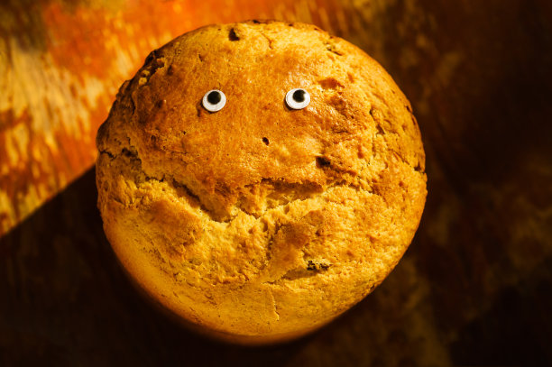 特写自制的新鲜脆皮面包在木制的乡村背景与眼睛和微笑形状的裂缝图片下载