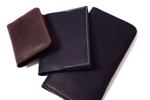 手工制作的棕色持卡人，蓝色护照封面和黑色钱包孤立在白色背景的特写。孤立的手工奢侈品配件库存照片。图片下载