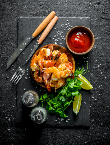 把虾放在石板上，配上香料、番茄酱和香草。图片下载