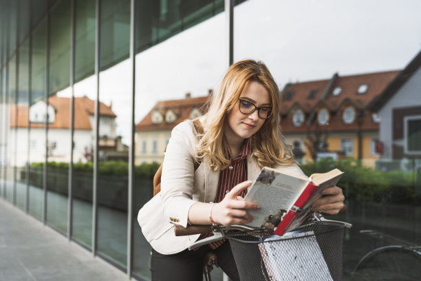 红发少女骑着自行车看书图片下载