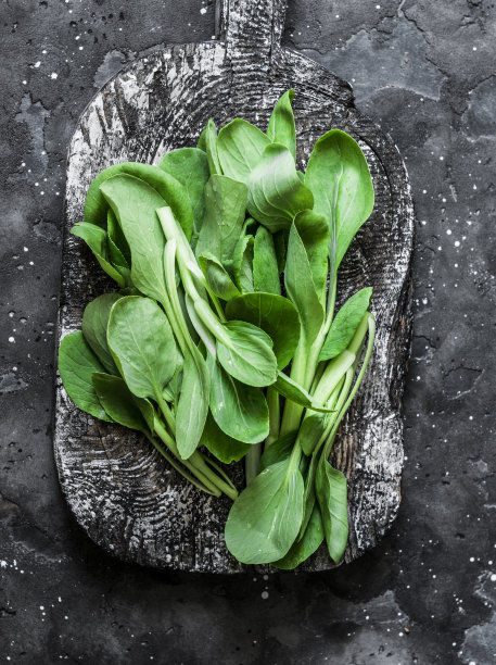 小白菜放在乡村木板上，背景为黑色。健康食品原料图片下载