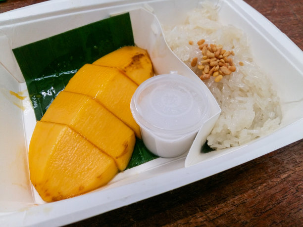 泰国芒果糯米饭配椰奶甜点，纸盒配木背景，泰国甜点图片下载