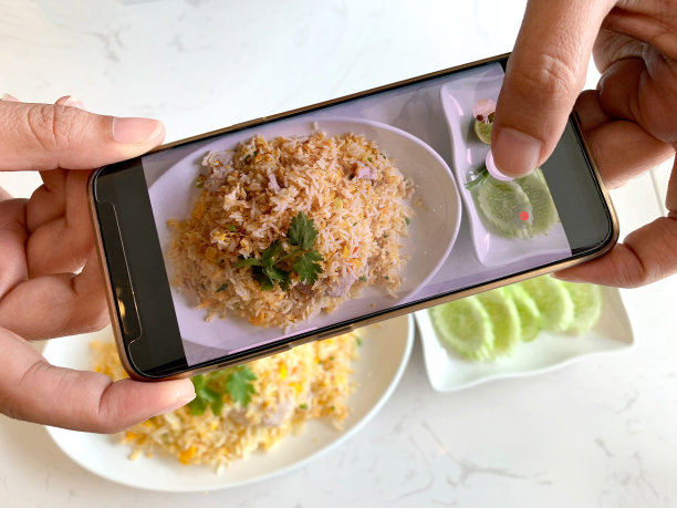 女性用智能手机记录下放在厨房桌子上的食物。图片下载