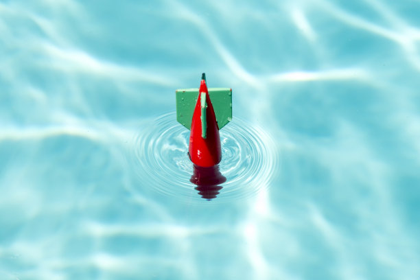 带着水花和水波进入游泳池表面的玩具导弹图片下载