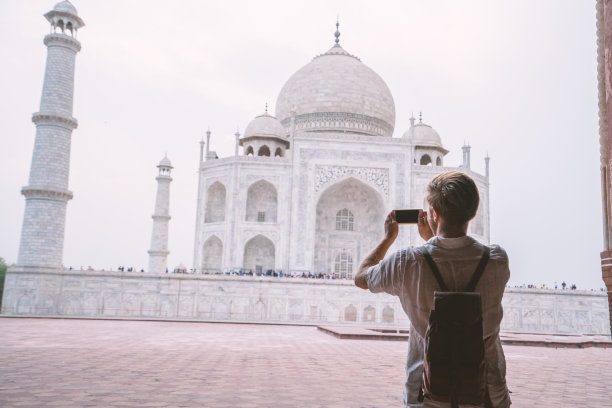 印度阿格拉，一名年轻游客用智能手机给著名的泰姬陵拍照。亚洲人旅游概念图片下载