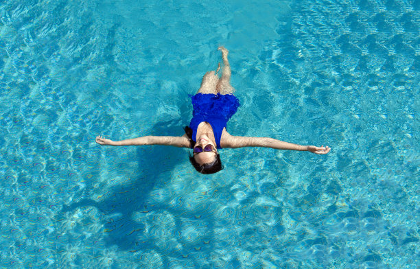 亚洲女孩与游泳套房和太阳眼镜放松在游泳池图片下载