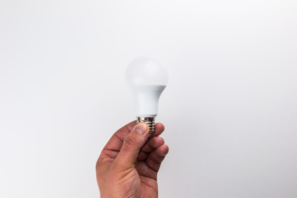 白色背景上，由插孔从中间侧面手持的Led灯泡图片下载