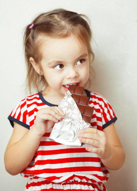 年轻的女士吃锡纸包的巧克力图片下载