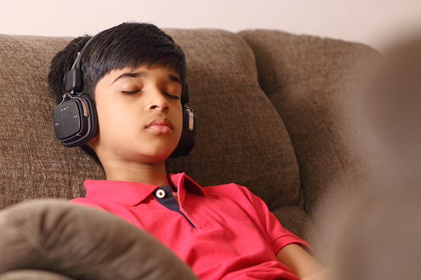 印度小男孩用耳机听音乐图片下载
