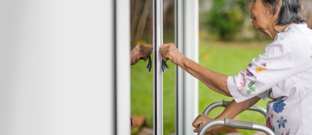 老妇人用钥匙打开前门。图片下载