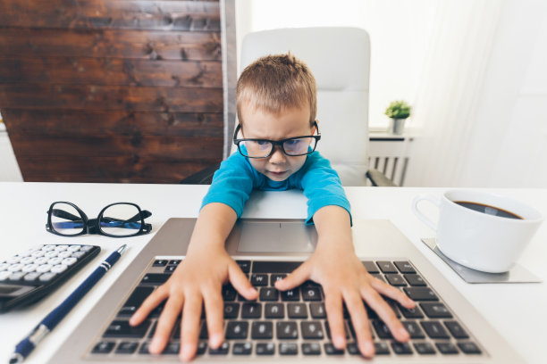 可爱的孩子戴着眼镜使用笔记本电脑图片下载