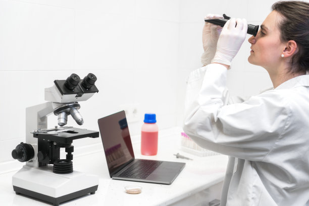 法医学实验室工作人员用折射计和显微镜研究样本，桌上放笔记本电脑，法医学。图片下载