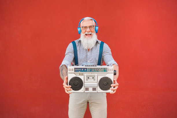 快乐的老年人与立体声音响播放音乐-时髦的成熟的家伙有乐趣地听着老式收音机-快乐的老年人生活方式概念-关注他的脸图片下载