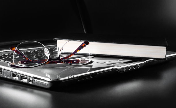 笔记本电脑键盘上放着书的眼镜。图片下载