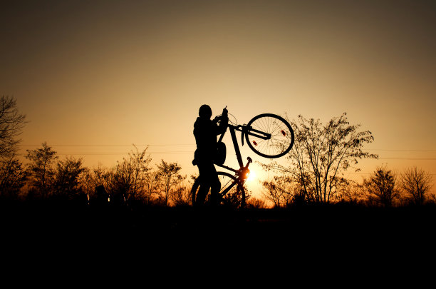 一个男孩的剪影与自行车的背景在明亮的夕阳老式风格图片下载