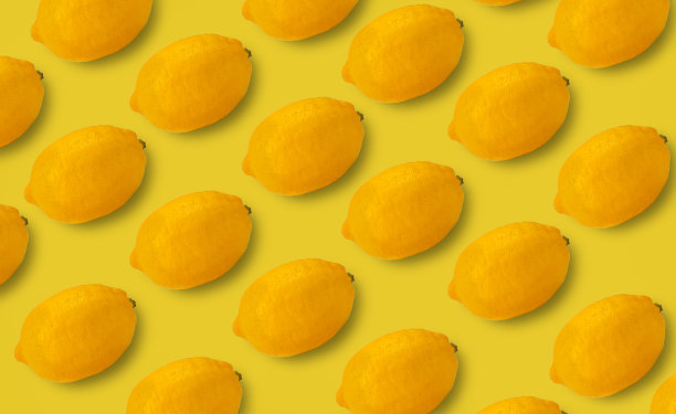 许多新鲜的柠檬在明亮的黄色背景。这是一个重复的装饰设计。图片下载