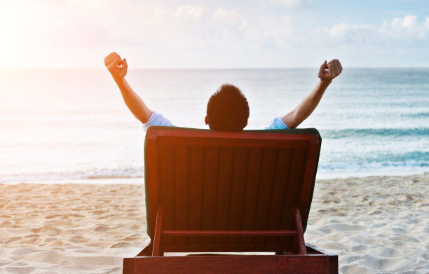 男人在椅子上放松，享受着海滩图片下载