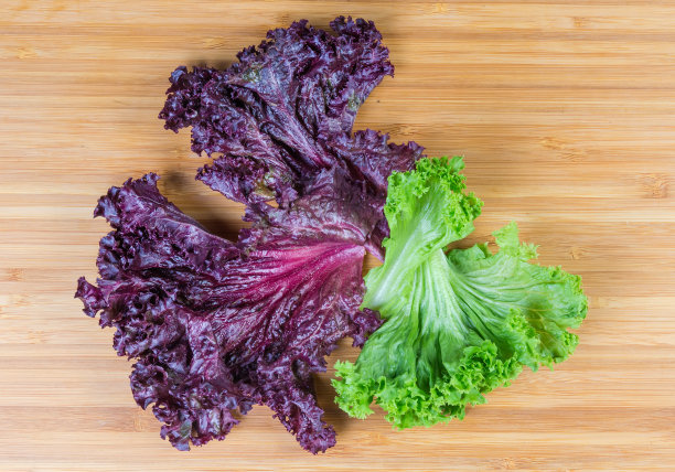 红色和绿色的莴苣叶子在木质表面，俯视图图片下载