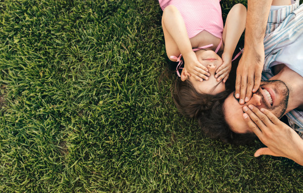 俯视图的形象，快乐英俊的父亲和可爱的孩子在公园里玩。上面是爸爸和他可爱的小女孩用手捂着眼睛玩躲猫猫的照片图片下载