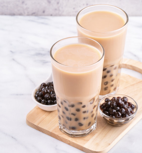 台湾流行饮品-珍珠奶茶与珍珠球饮用玻璃在大理石白色桌子木制托盘背景，近，复制空间素材图片