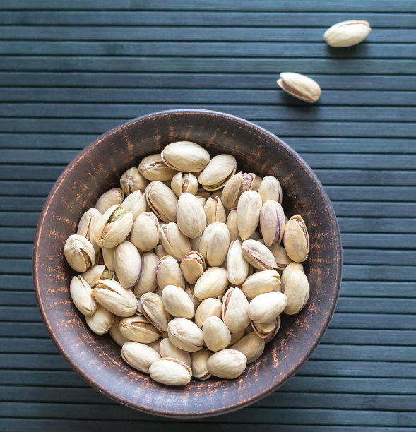 健康的食物背景图片近距离开心果。俯视图果仁开心果在杯盘上图片下载