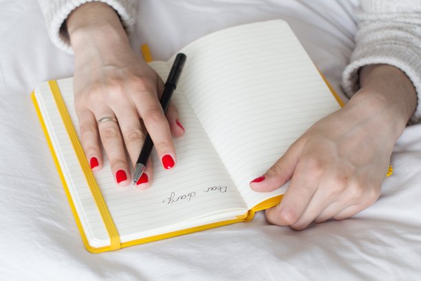 年轻女子在床上写日记图片下载