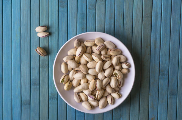 健康的食物背景图片近距离开心果。俯视图果仁开心果在杯盘上图片下载