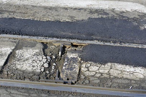 重建城市街道上火车轨道周围的破损沥青图片下载