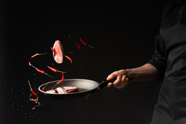 特写镜头。厨师用小红辣椒在黑底煎锅上烤鱼。水平的照片。海洋食品。健康食品。东方美食图片下载