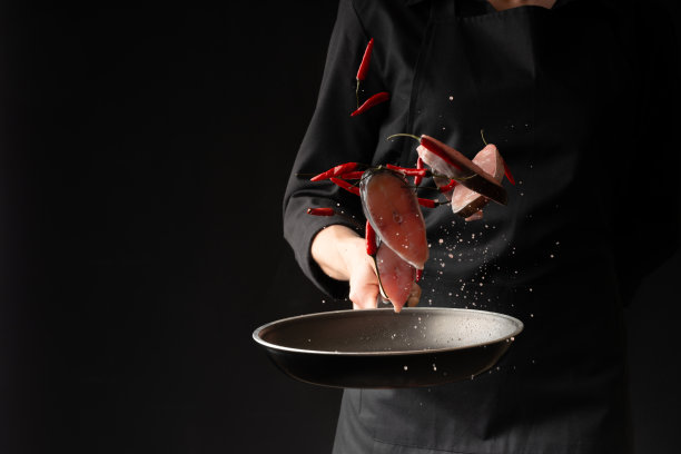 厨师在黑底煎锅上用小红辣椒煎鱼。水平的照片。海洋食品。健康食品。东方美食,禁止图片下载