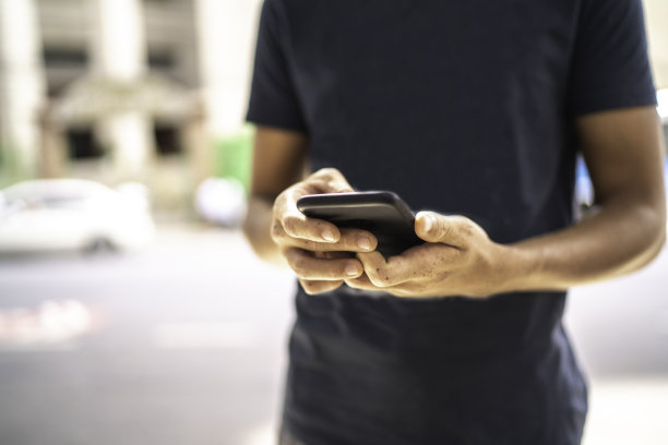 一个年轻人在街上用手机的特写图片下载