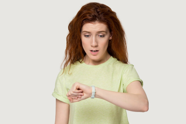 着急的红发女孩看着手表看时间图片下载