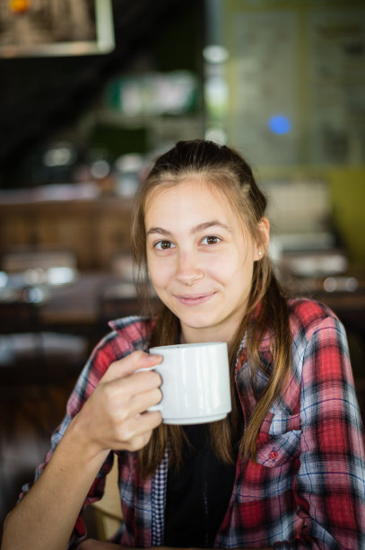 美丽的白人女人微笑着，手里拿着一杯白色的咖啡图片下载