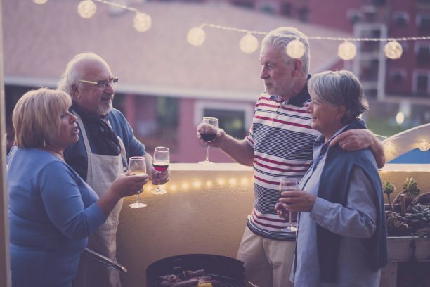 晚上朋友人们一起庆祝与红和白葡萄酒一起玩-城市的阳台-烧烤和友谊的成年老年男人和女人-高加索成熟的夫妇图片下载