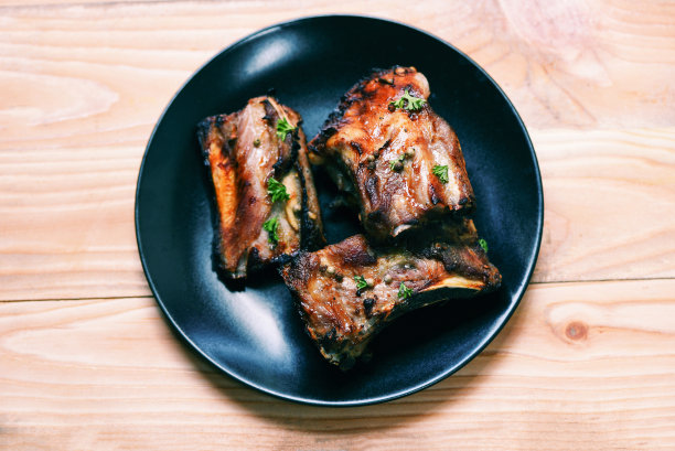 烧烤猪肋排用香草和香料烤盘盛在木桌上，烧烤猪肋排切片图片下载