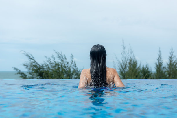 暑假和假期。女性生活方式放松和快乐在豪华游泳池日光浴，夏日在酒店的海滩度假。夏天的概念图片下载