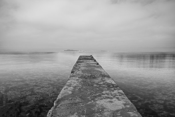 海上的木制码头和水面上天空的倒影。长曝光，黑白照片图片下载