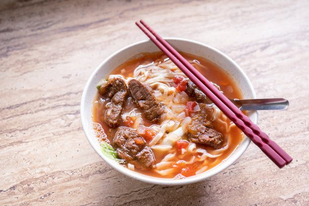 牛肉面拉面配番茄酱肉汤在明亮的木桌上，台湾著名的中式美食，近距离，俯视图，拷贝空间图片下载