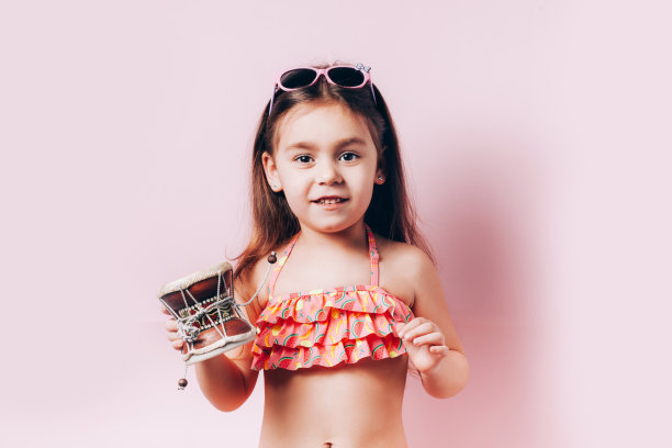 可爱的小女孩穿着泳衣打小鼓。图片下载